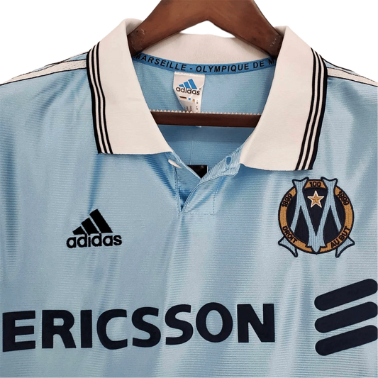 https://cdn.shopify.com/s/files/1/0826/7228/8075/files/19981999-olympique-de-marseille-ericsson-away-retro-jersey-at-govintagejersey-store-957106.webp?v=1741199390