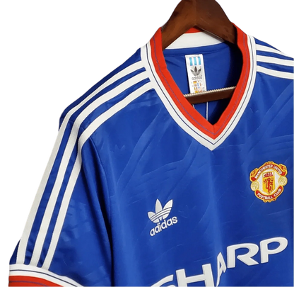 https://cdn.shopify.com/s/files/1/0826/7228/8075/files/19861988-manchester-united-sharp-blue-third-retro-kit-classickits433-411956.webp?v=1741199196