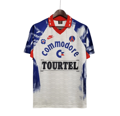 https://cdn.shopify.com/s/files/1/0826/7228/8075/files/19931994-paris-saint-germain-commodore-away-white-retro-457661.webp?v=1741199392