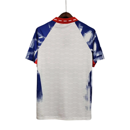 https://cdn.shopify.com/s/files/1/0826/7228/8075/files/19931994-paris-saint-germain-commodore-away-white-retro-756711.webp?v=1741199393