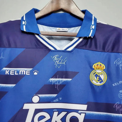 https://cdn.shopify.com/s/files/1/0826/7228/8075/files/19941996-real-madrid-teka-blue-away-retro-kit-classickits433-482271.webp?v=1741199039