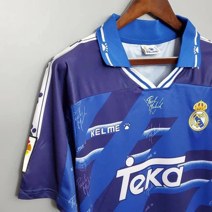 https://cdn.shopify.com/s/files/1/0826/7228/8075/files/19941996-real-madrid-teka-blue-away-retro-kit-classickits433-755050.webp?v=1741199039