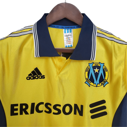 https://cdn.shopify.com/s/files/1/0826/7228/8075/files/19981999-olympique-de-marseille-ericsson-away-retro-jersey-445110.webp?v=1741199401