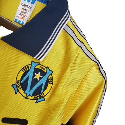 https://cdn.shopify.com/s/files/1/0826/7228/8075/files/19981999-olympique-de-marseille-ericsson-away-retro-jersey-691650.webp?v=1741199400