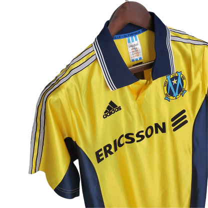 https://cdn.shopify.com/s/files/1/0826/7228/8075/files/19981999-olympique-de-marseille-ericsson-away-retro-jersey-782980.webp?v=1741199403