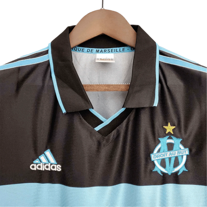 https://cdn.shopify.com/s/files/1/0826/7228/8075/files/19992000-olympique-de-marseille-ericsson-home-retro-kit-classickits433-409793.webp?v=1741199401